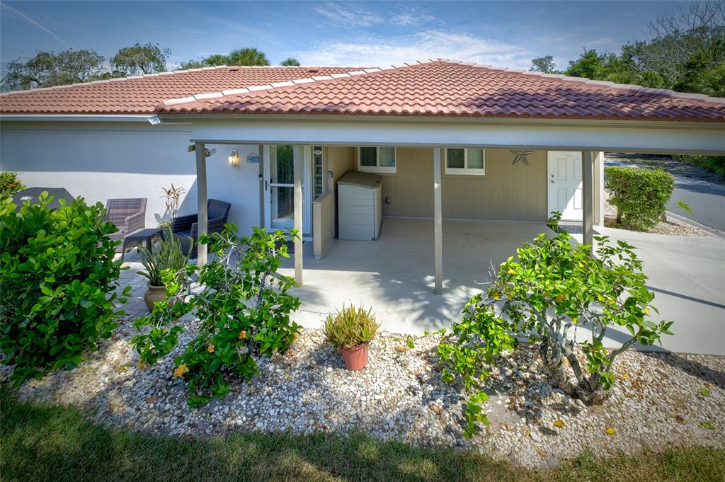 A covered patio area features a concrete floor, beige siding, and a white door — 161 VISTA HERMOSA CIRCLE UNIT 26A, SARASOTA, FL