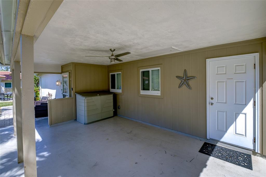 A covered patio features a white door, a ceiling fan, and a decorative wall star — 161 VISTA HERMOSA CIRCLE UNIT 26A, SARASOTA, FL