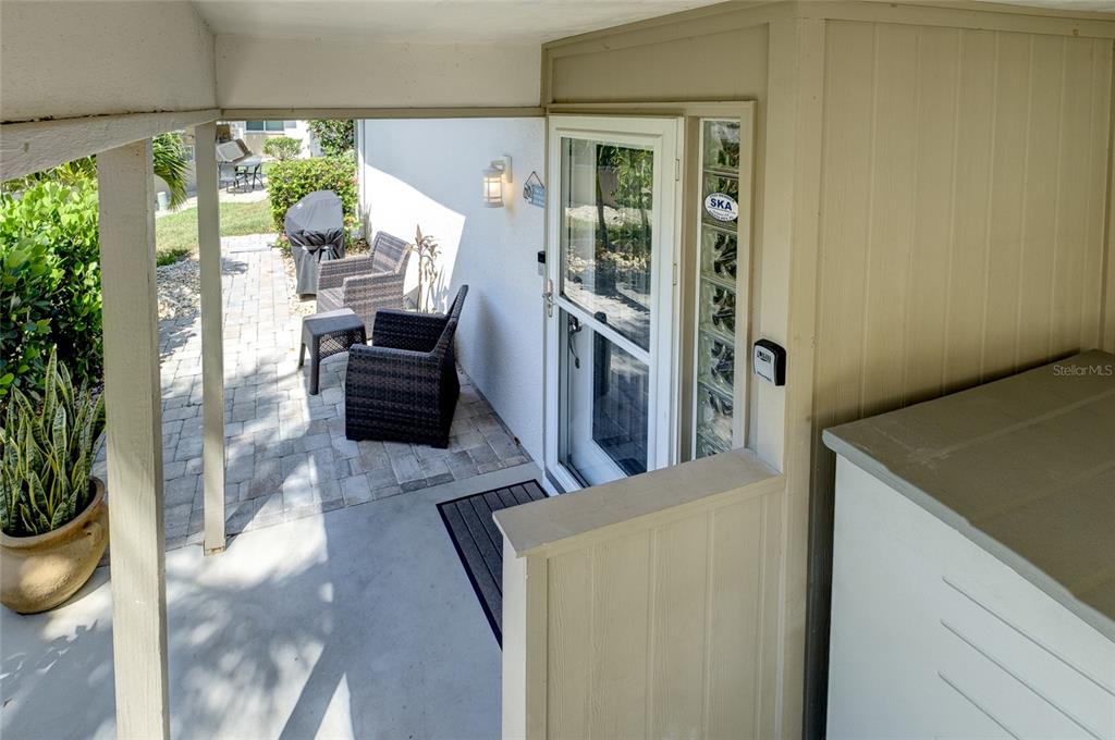 A covered patio features a paved floor, outdoor seating, and a glass-paneled door — 161 VISTA HERMOSA CIRCLE UNIT 26A, SARASOTA, FL