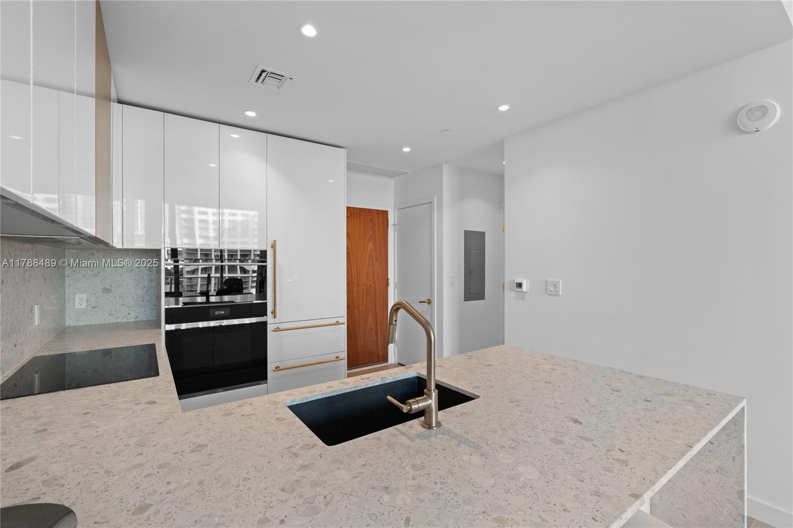 A modern kitchen features white cabinetry, a speckled stone island, and a black sink — 2678 Tigertail Ave # 615, Miami FL 33133, MIAMI, FL
