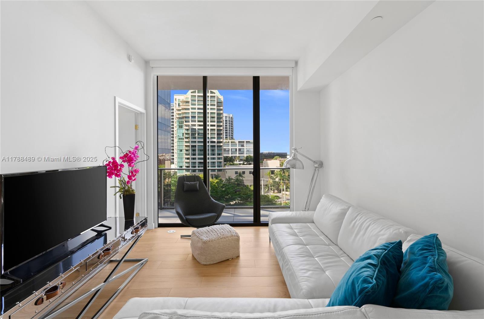 A modern living room features a white sofa, a dark armchair, and floor-to-ceiling windows — 2678 Tigertail Ave # 615, Miami FL 33133, MIAMI, FL