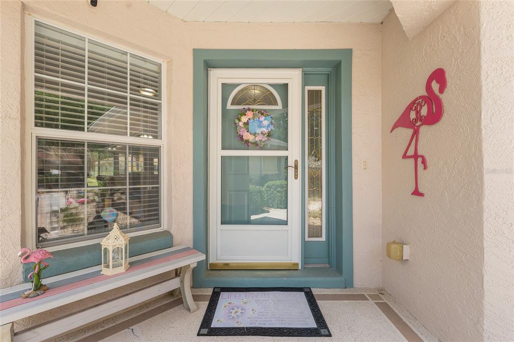 A front entryway features a white storm door, a side window, and a pink flamingo decoration — 9511 SW 93RD LOOP, OCALA, FL