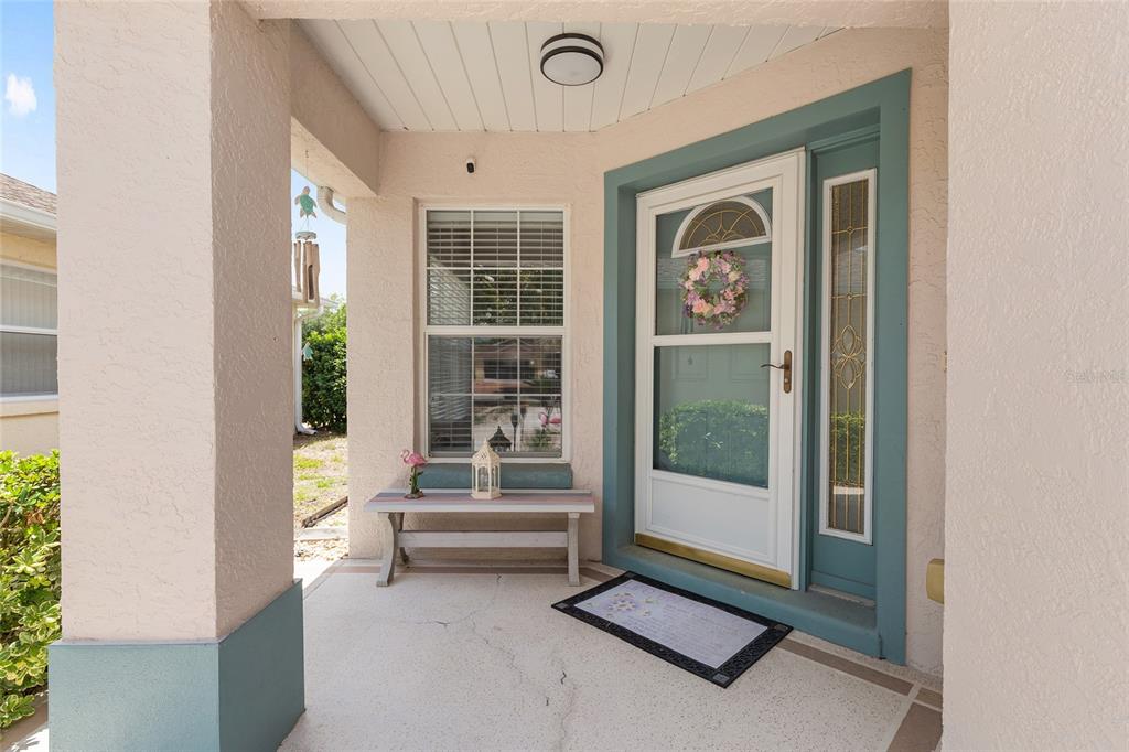 A covered front porch features a white door with a storm door and a bench — 9511 SW 93RD LOOP, OCALA, FL
