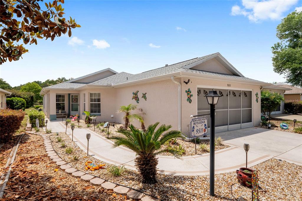A single-story house with a beige stucco exterior, a garage, and a curved walkway — 9511 SW 93RD LOOP, OCALA, FL