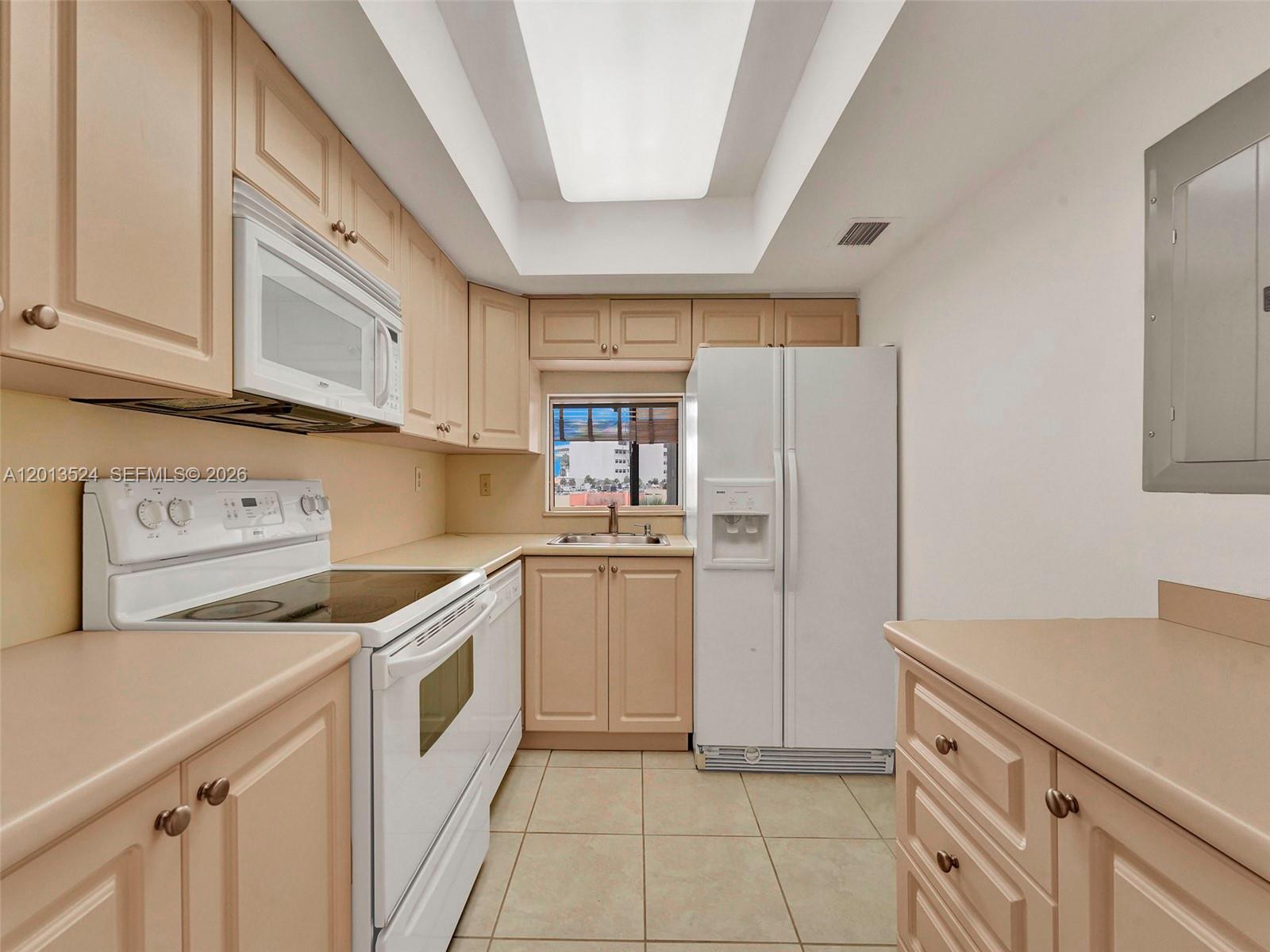 A galley kitchen features light wood cabinets, white appliances, tile flooring, and a recessed ceiling — 9420 W Flagler St # 312, Miami FL 33174, MIAMI, FL
