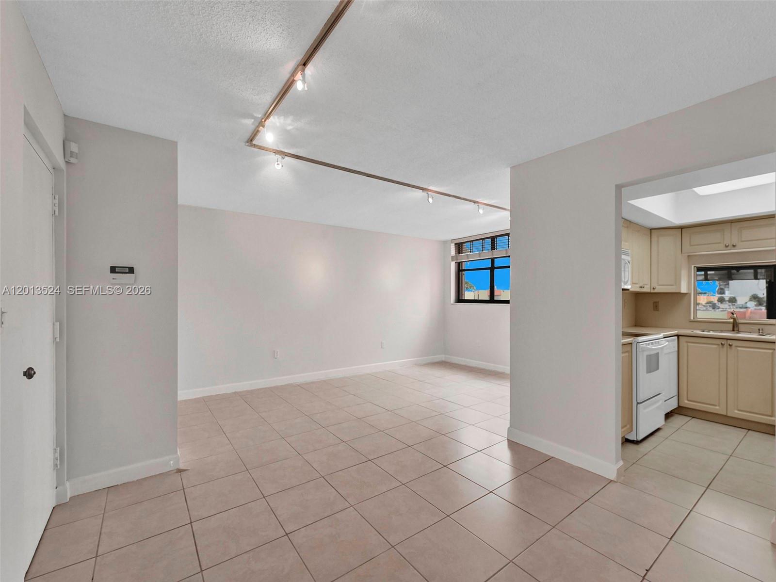 An open-concept living area with tile flooring, track lighting, and an adjacent kitchen — 9420 W Flagler St # 312, Miami FL 33174, MIAMI, FL