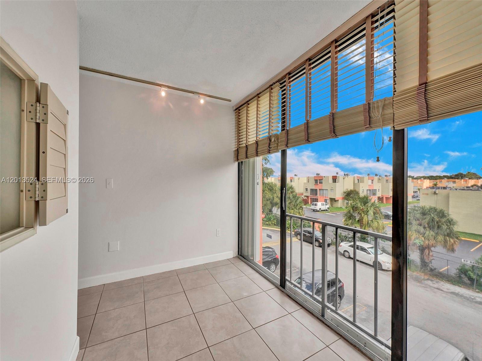 A small room with tile flooring, track lighting, and a sliding glass door to a balcony — 9420 W Flagler St # 312, Miami FL 33174, MIAMI, FL