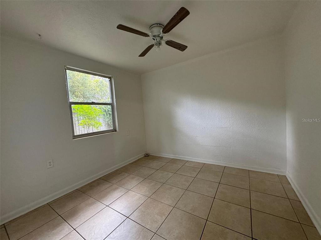An empty bedroom features white walls, a ceiling fan, and light-colored tile flooring — 2547 S MILLS AVENUE UNIT 2, ORLANDO, FL