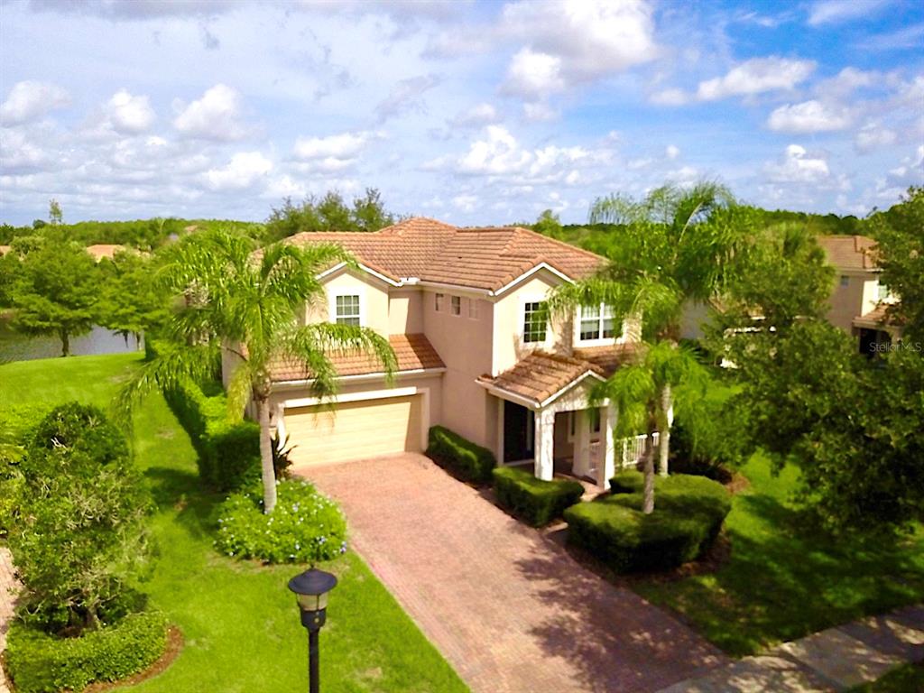 An aerial view of a two-story suburban house with a tiled roof and brick driveway — 11848 ZELKOVA LANE, ORLANDO, FL