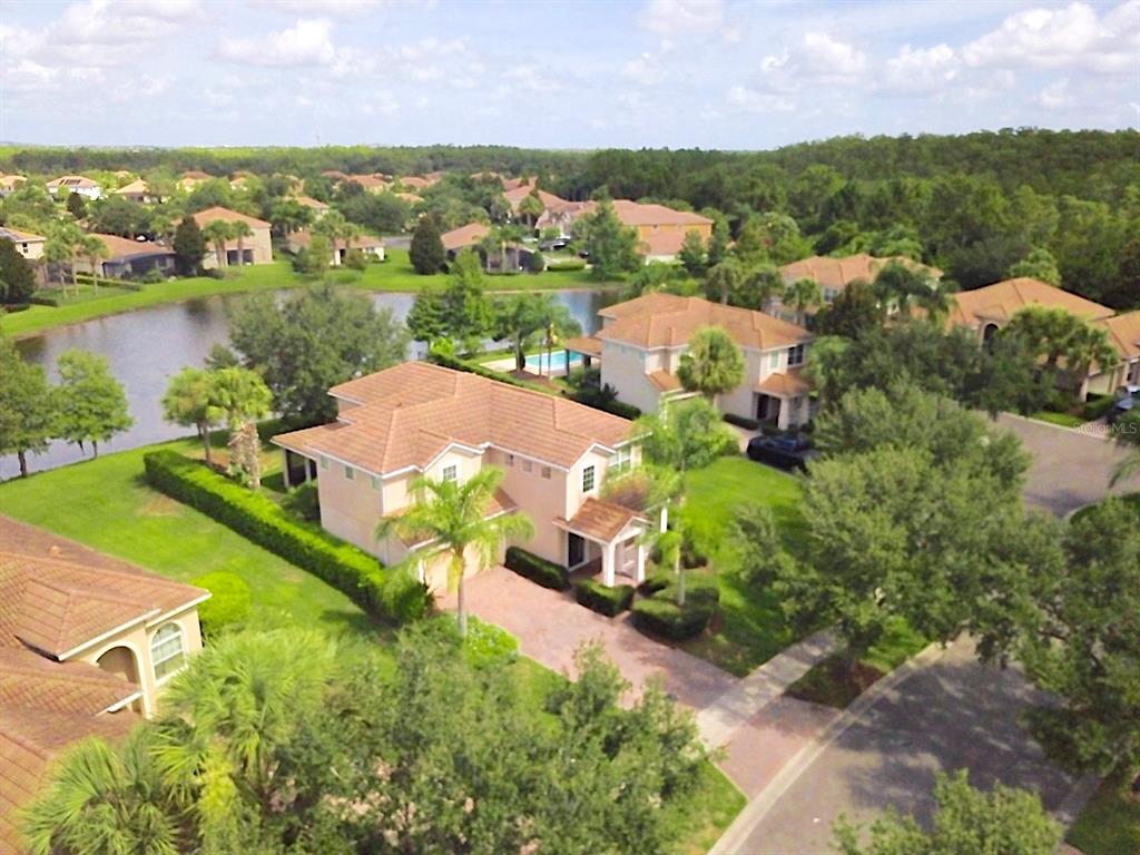 An aerial view shows a two-story suburban house with a tiled roof near a lake — 11848 ZELKOVA LANE, ORLANDO, FL