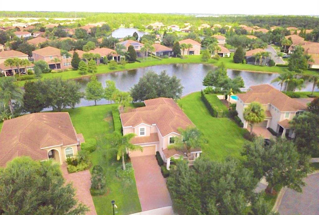 An aerial view shows several suburban houses surrounding a central pond with lush green landscaping — 11848 ZELKOVA LANE, ORLANDO, FL