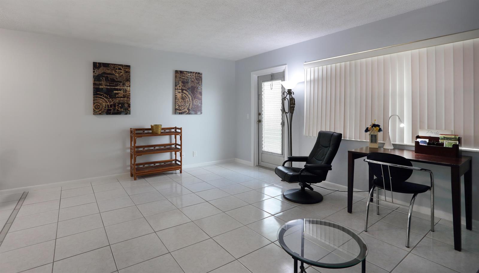 A room with white tiled floors, a desk, a black chair, and wall art — 331 Windsor O, West Palm Beach FL 33417, WEST PALM BEACH, FL