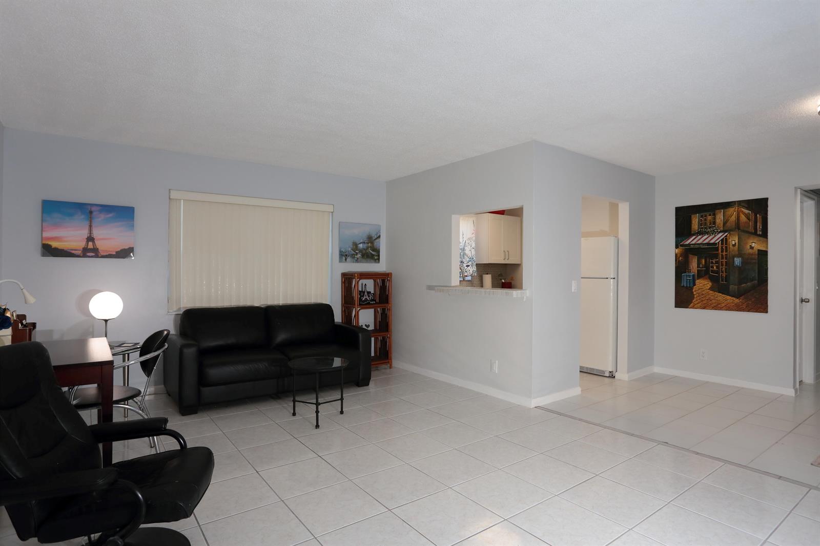 A living room with light gray walls, white tile flooring, and a black leather sofa — 331 Windsor O, West Palm Beach FL 33417, WEST PALM BEACH, FL