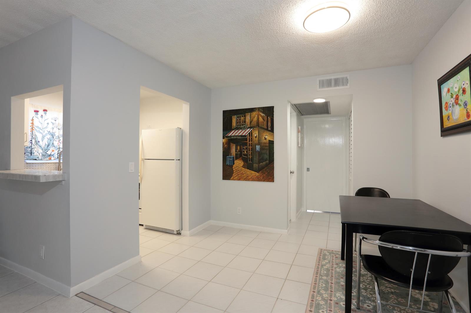 A dining area with white tile floors, a black table, and a painting on the wall — 331 Windsor O, West Palm Beach FL 33417, WEST PALM BEACH, FL