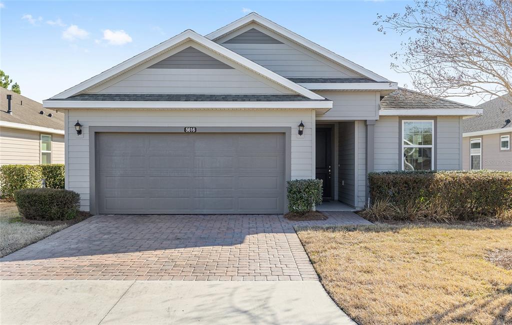 A single-story house features a gray garage, a paved driveway, and a small front yard — 5616 NW 37TH LANE ROAD, OCALA, FL