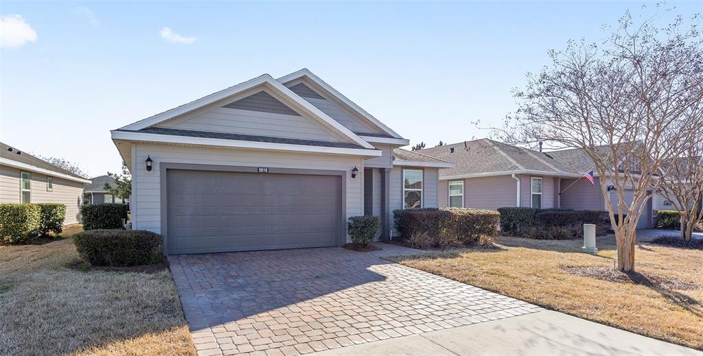 A single-story house with a two-car garage and a paved driveway under a blue sky — 5616 NW 37TH LANE ROAD, OCALA, FL