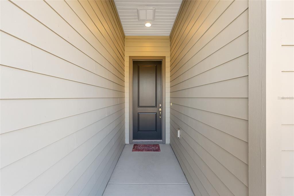 A recessed front entryway features a dark door, light-colored horizontal siding, and a concrete floor — 5616 NW 37TH LANE ROAD, OCALA, FL