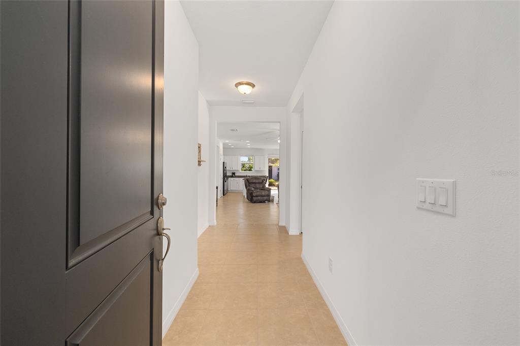 A view from an open front door looking down a hallway toward a kitchen — 5616 NW 37TH LANE ROAD, OCALA, FL