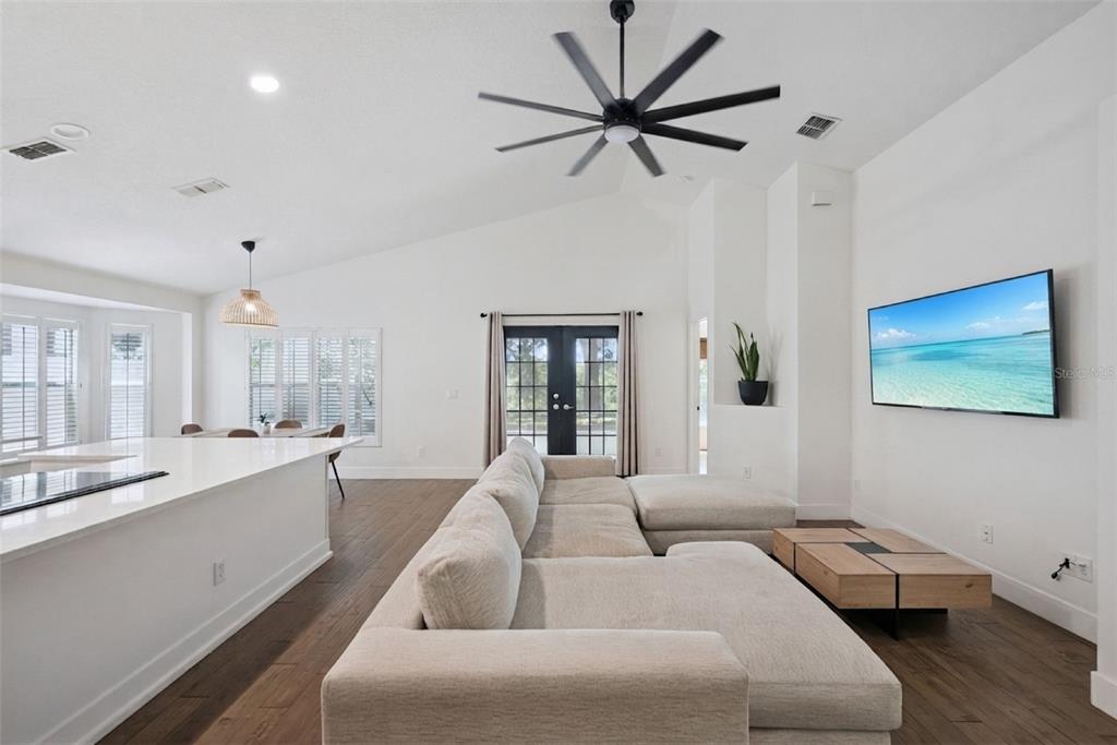 A living room with a large sectional sofa, a ceiling fan, and a wall-mounted television — 2080 CRANBERRY ISLES WAY, APOPKA, FL