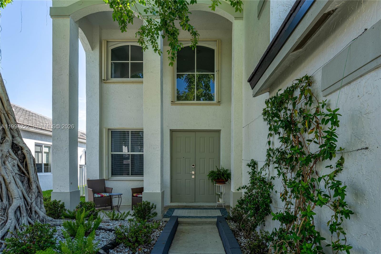 The exterior of a two-story house features a double front door and a covered entryway — 910 Sunflower Cir, Weston FL 33327, WESTON, FL