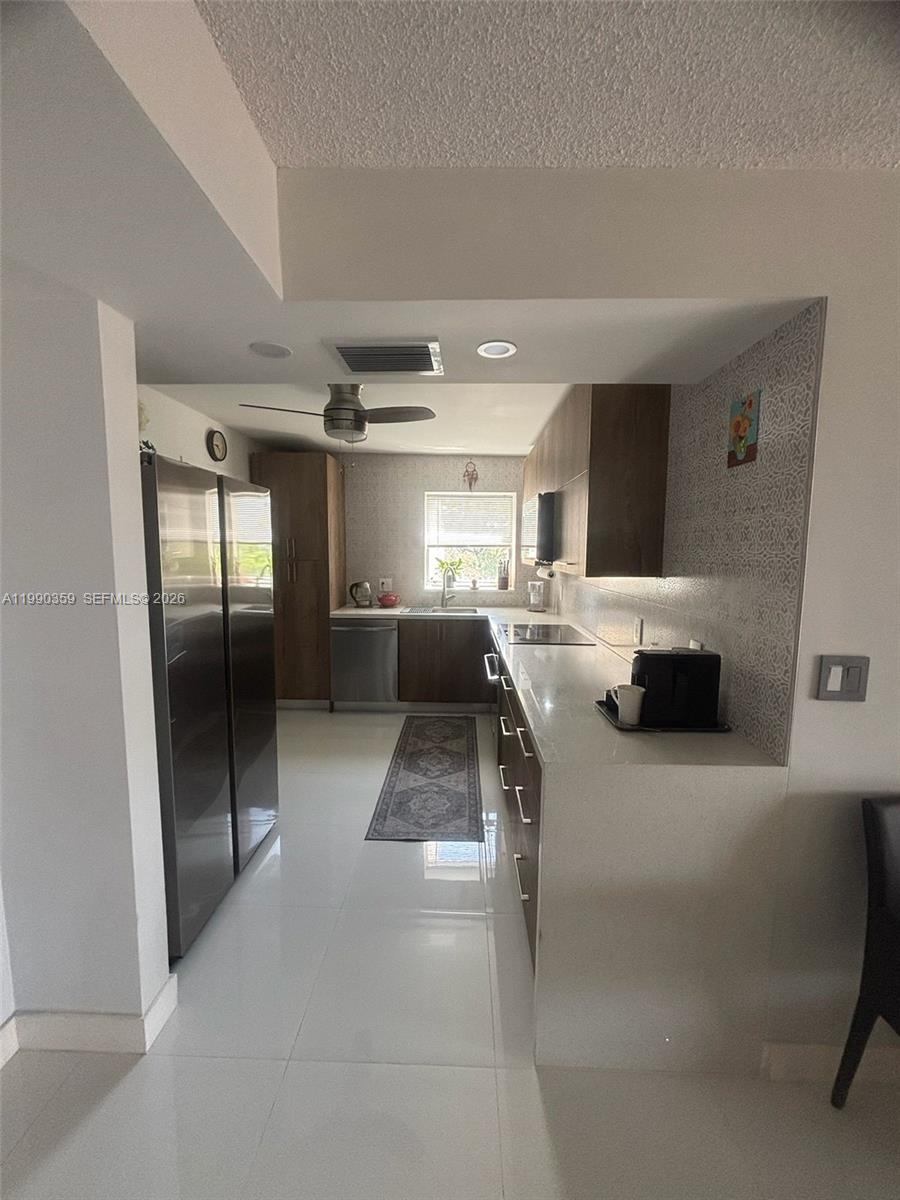 A galley kitchen features stainless steel appliances, wood cabinetry, and white countertops — 1865 S Ocean Dr # 4F, Hallandale Beach FL 33009, HALLANDALE BEACH, FL