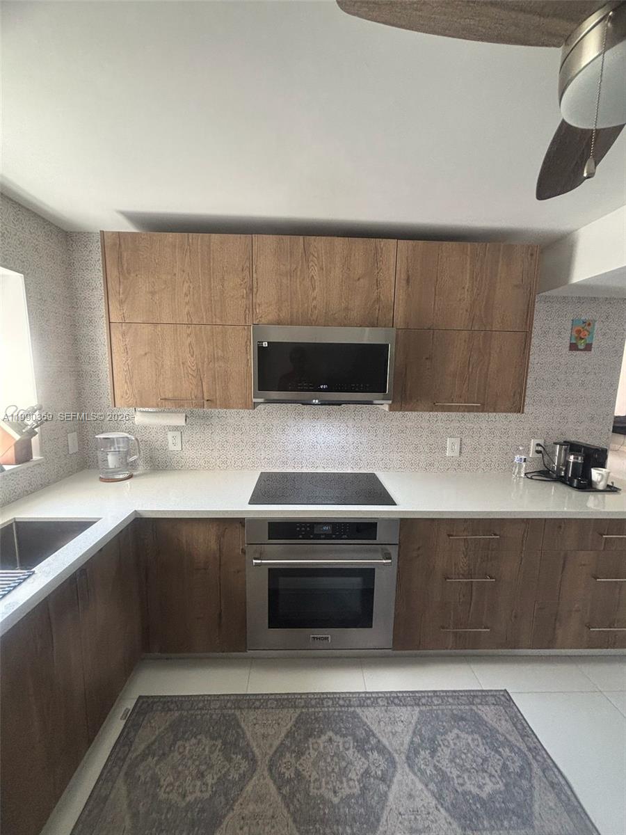 A kitchen features wood-grain cabinets, a stainless steel oven, a microwave, and white countertops — 1865 S Ocean Dr # 4F, Hallandale Beach FL 33009, HALLANDALE BEACH, FL