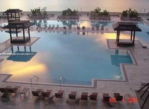 An elevated view of a swimming pool with two cabanas and lounge chairs on the deck — 1830 S Ocean Dr # 4007, Hallandale Beach FL 33009, HALLANDALE BEACH, FL