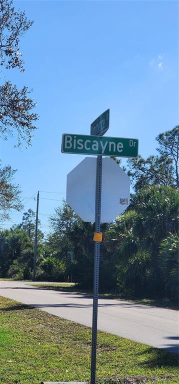 A street sign for Biscayne Drive stands above a blank stop sign near a paved road — 1173 BISCAYNE DRIVE, PORT CHARLOTTE, FL