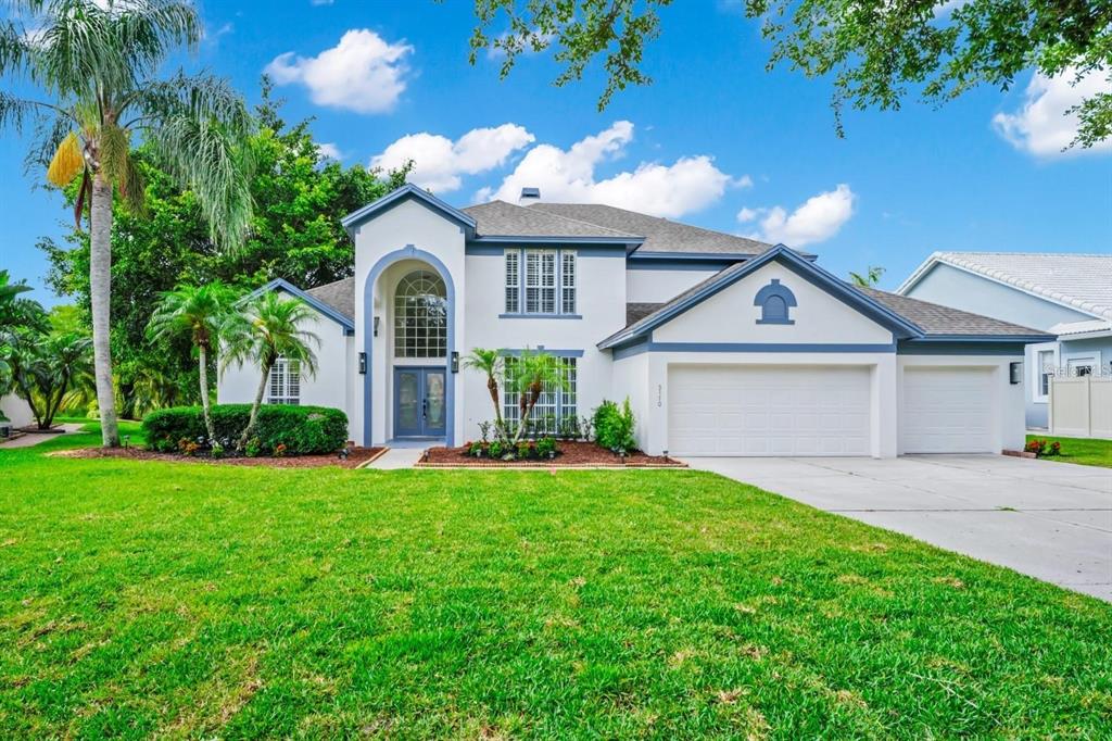A two-story white house with blue trim, a multi-car garage, and a manicured front lawn — 3170 ZAHARIAS DRIVE, ORLANDO, FL