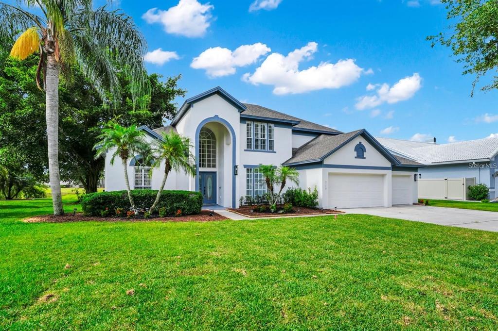 A two-story white house with blue trim, a multi-car garage, and a landscaped front yard — 3170 ZAHARIAS DRIVE, ORLANDO, FL
