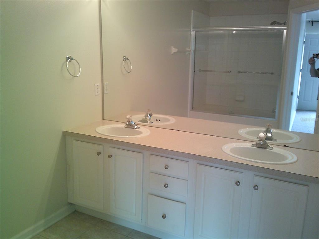 A bathroom features a double vanity with white cabinets, a large mirror, and a shower — 6292 TWAIN STREET UNIT 107, ORLANDO, FL