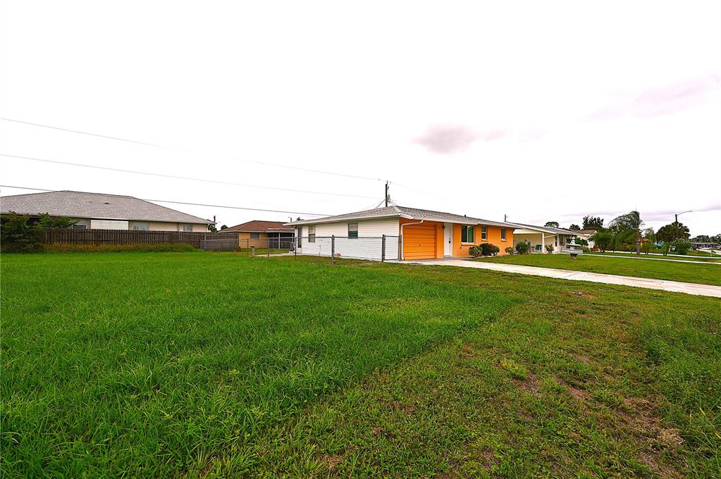 A single-story house with an orange garage door sits on a large, grassy lot — 232 SAN MARINO AVENUE, NORTH PORT, FL