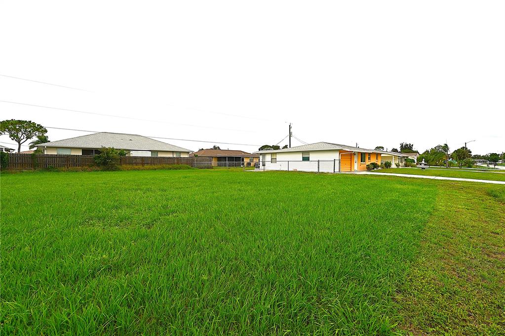 A large, grassy vacant lot sits next to a single-story house with a garage — 232 SAN MARINO AVENUE, NORTH PORT, FL