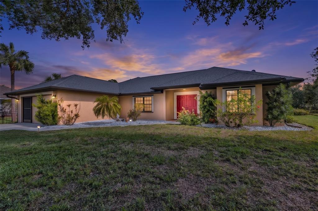 A single-story house with a tan exterior, red double front doors, and a dark roof — 2338 KELSEY COURT, NORTH PORT, FL
