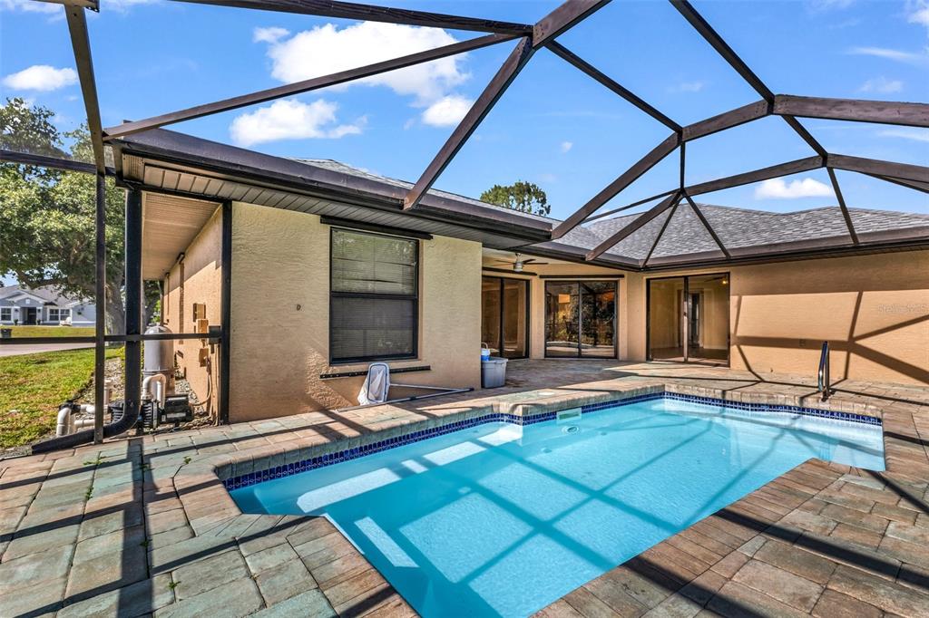 A screened-in patio features a rectangular swimming pool surrounded by stone pavers — 2338 KELSEY COURT, NORTH PORT, FL