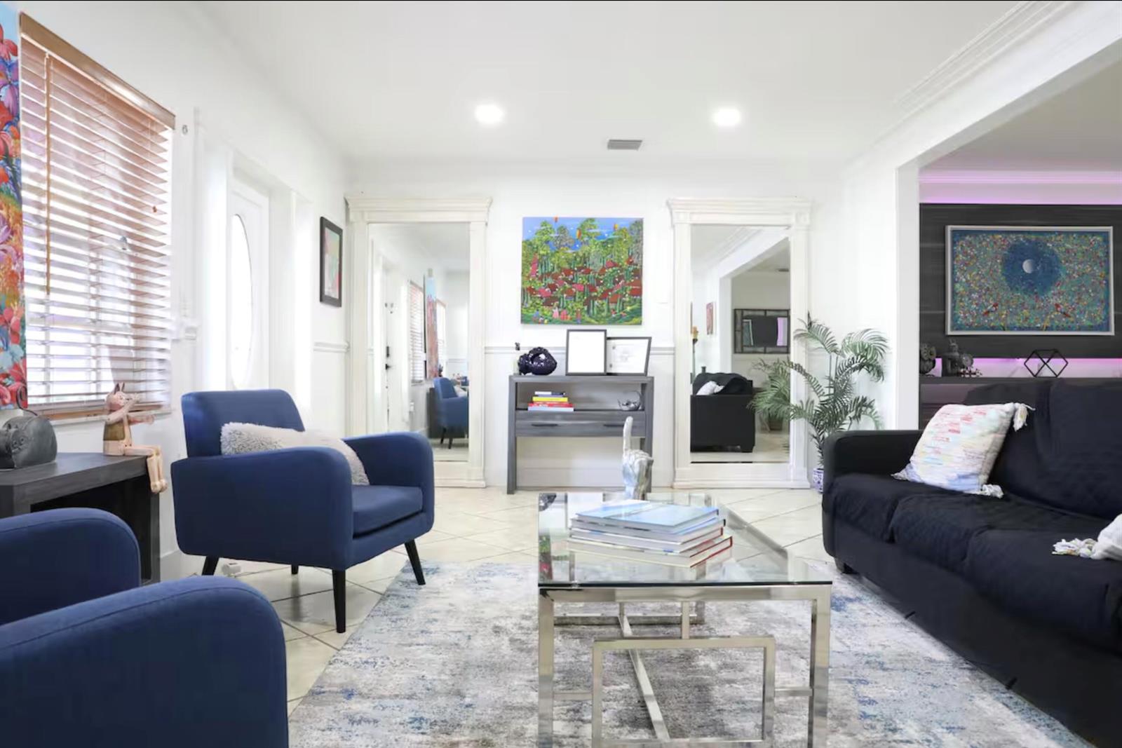 A living room features blue armchairs, a black sofa, a glass coffee table, and mirrors — 150 NE 146th Street NE, Miami FL 33161, MIAMI, FL