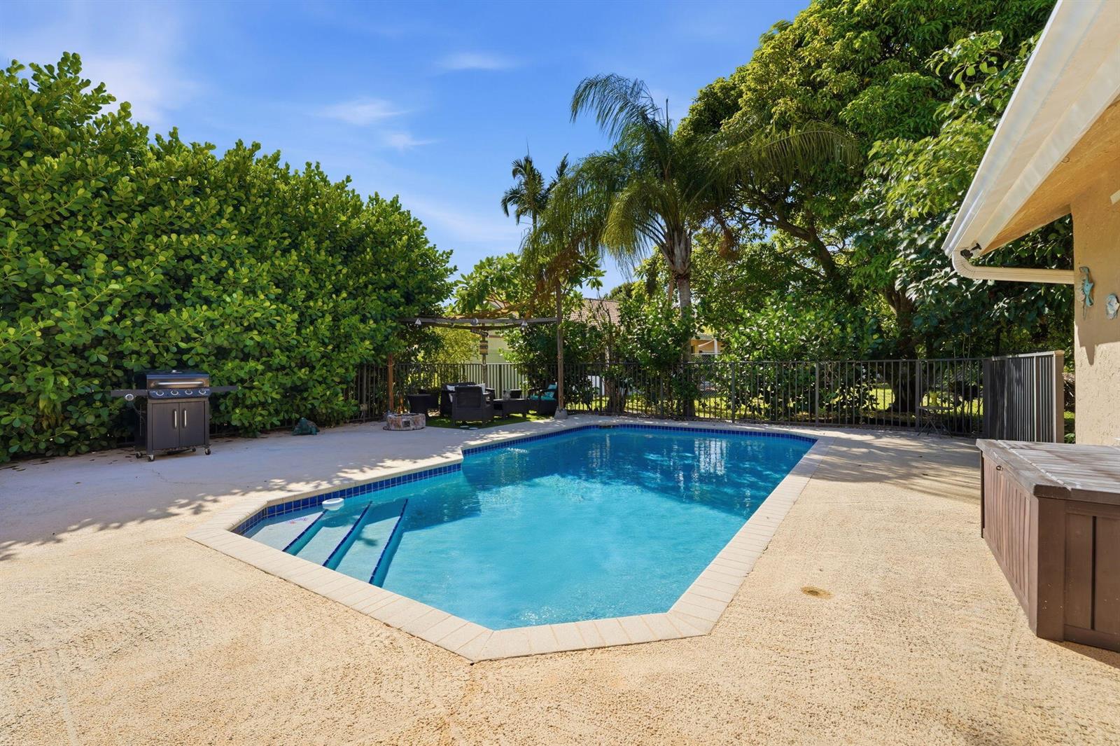 A backyard features a rectangular swimming pool with steps, a patio, and surrounding lush landscaping — 9577 Majestic Way, Boynton Beach FL 33437, BOYNTON BEACH, FL