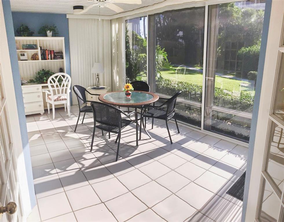 A sunroom with tiled floors, a dining set, and a desk overlooking a grassy yard — 1344 SIESTA BAYSIDE DRIVE UNIT 1344-D, SARASOTA, FL