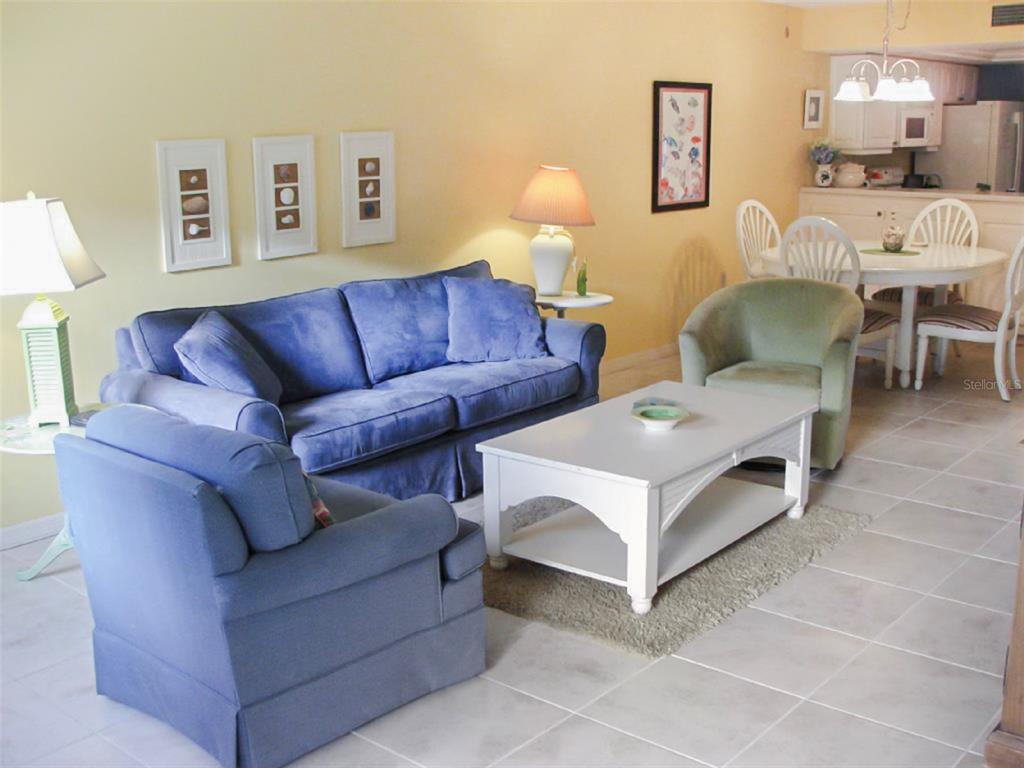 A living room with a blue sofa and armchair, a white coffee table, and dining area — 1344 SIESTA BAYSIDE DRIVE UNIT 1344-D, SARASOTA, FL