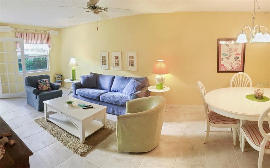 A living and dining area with tile floors, a blue sofa, and a round table — 1344 SIESTA BAYSIDE DRIVE UNIT 1344-D, SARASOTA, FL