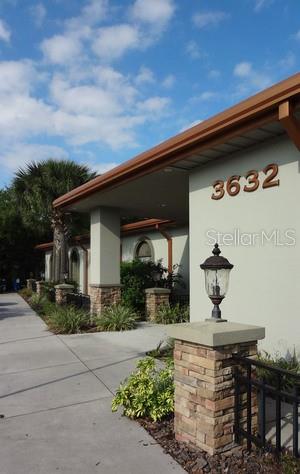The exterior of a building features a covered entrance with stone pillars and a lamp post — 3632 LAND O LAKES BOULEVARD UNIT 104-3, LAND O LAKES, FL