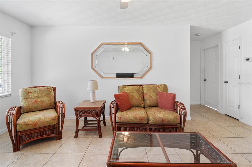 A living room features wicker furniture, a glass-topped coffee table, and a wall-mounted octagonal mirror — 1509 WYOMING AVENUE, ST CLOUD, FL