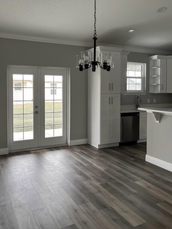 A dining area with wood-look flooring, a chandelier, white cabinets, and French doors to outside — 528 SE 35th Terrace, Okeechobee FL 34974, OKEECHOBEE, FL