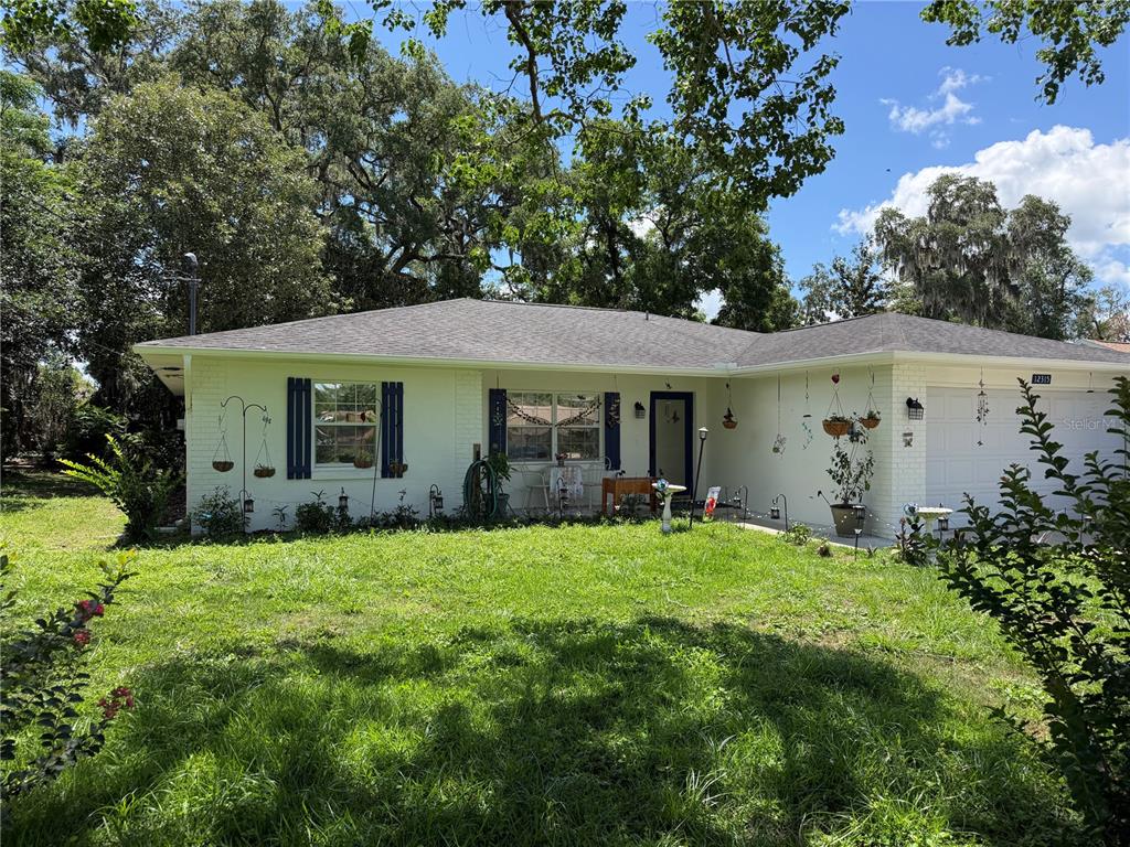 A single-story house with a white brick exterior, a gray roof, and a front lawn — 12315 SE 60TH TERRACE, BELLEVIEW, FL