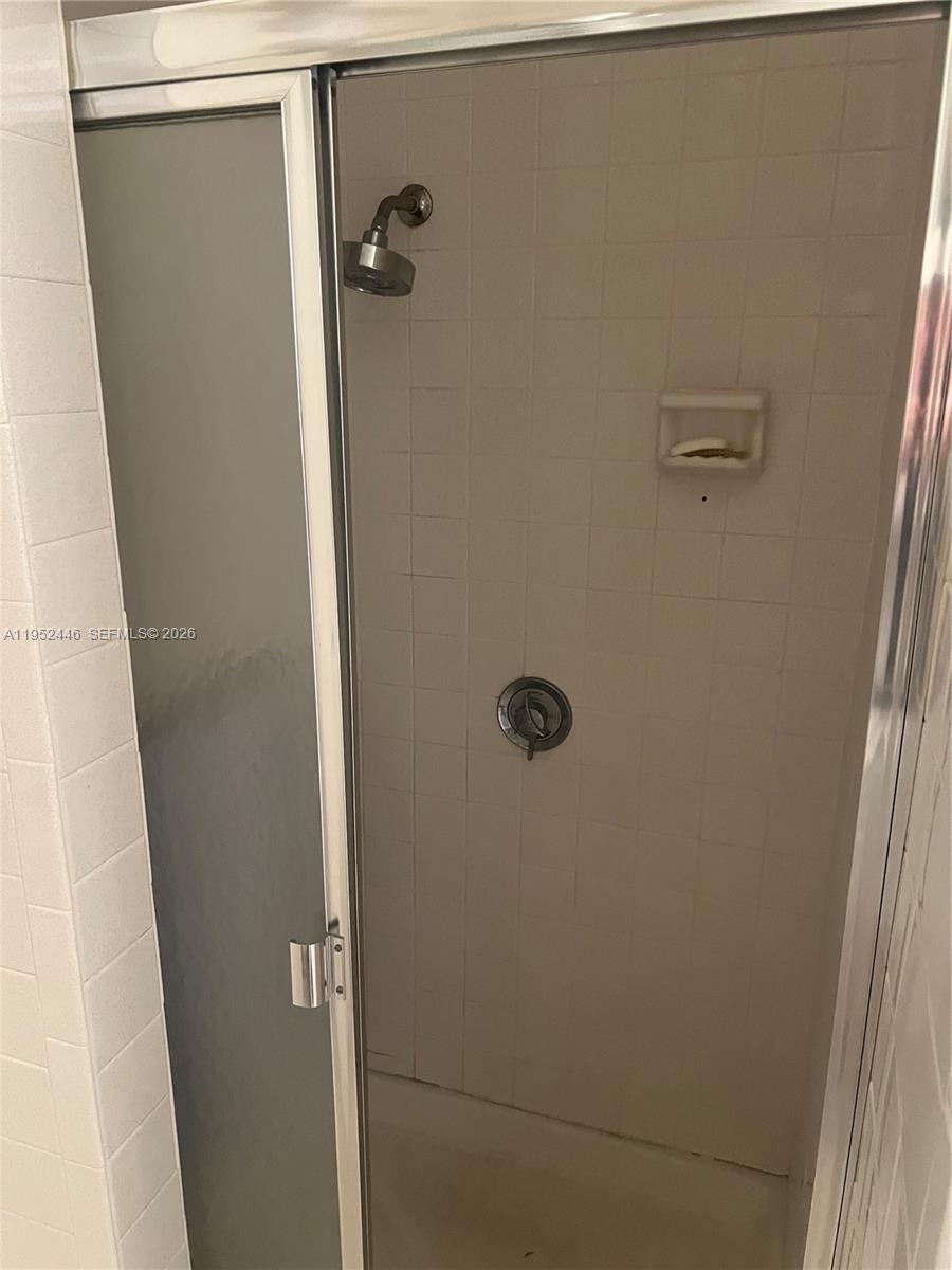 A walk-in shower features white tiled walls, a glass door, and a chrome showerhead — 9801 Collins Ave, Bal Harbour FL 33154, BAL HARBOUR, FL