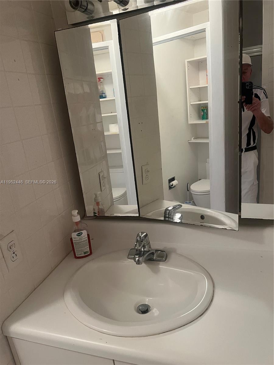 A bathroom vanity features a white sink, chrome faucet, and a mirrored medicine cabinet — 9801 Collins Ave, Bal Harbour FL 33154, BAL HARBOUR, FL
