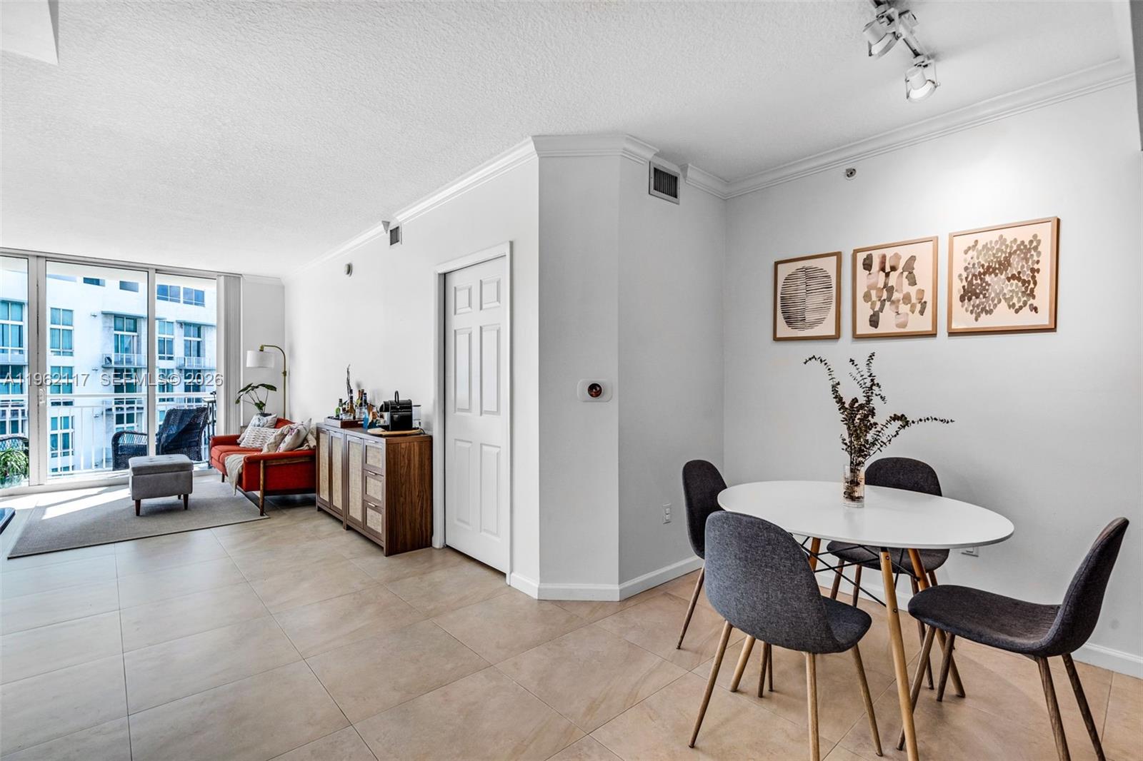 A bright living and dining area features tile floors, a white table, and a balcony — 2000 N Bayshore Dr # 909, Miami FL 33137, MIAMI, FL