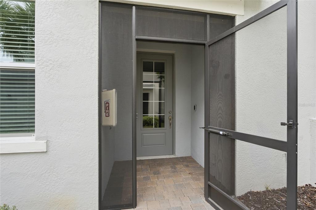 An open screen door leads to a gray front door with a glass pane — 14680 SYCAMORE COURT UNIT 3712, PUNTA GORDA, FL