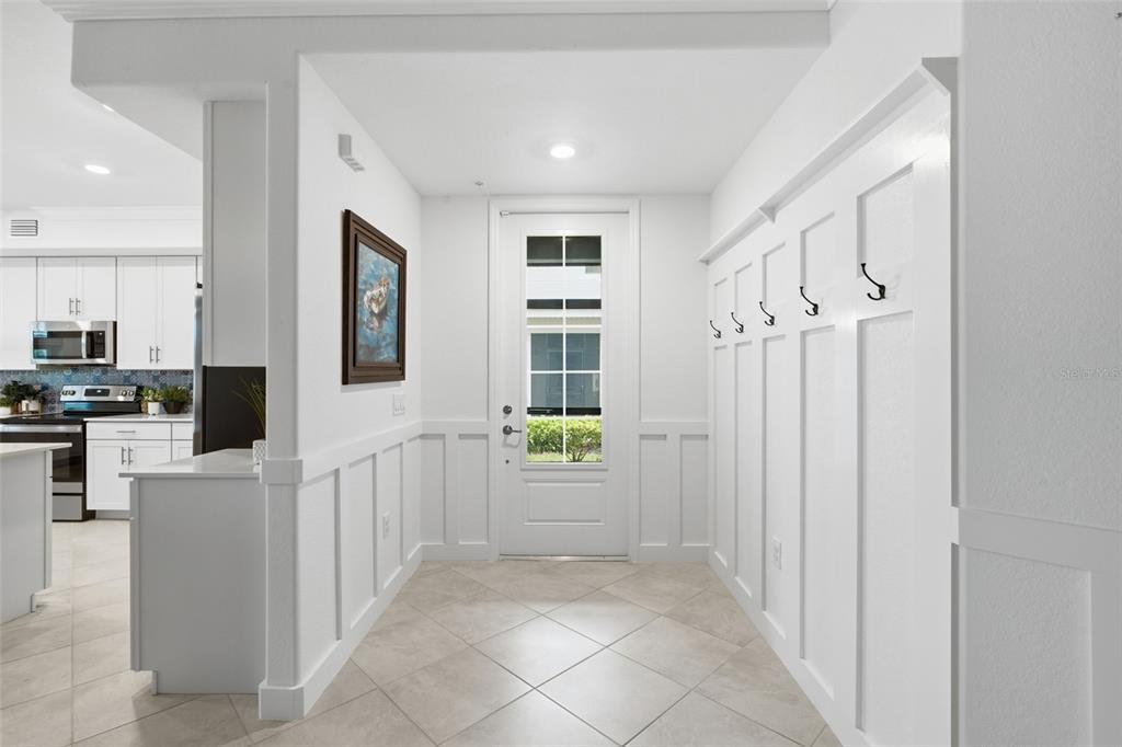 A bright entryway features white board-and-batten walls, coat hooks, and tile flooring — 14680 SYCAMORE COURT UNIT 3712, PUNTA GORDA, FL