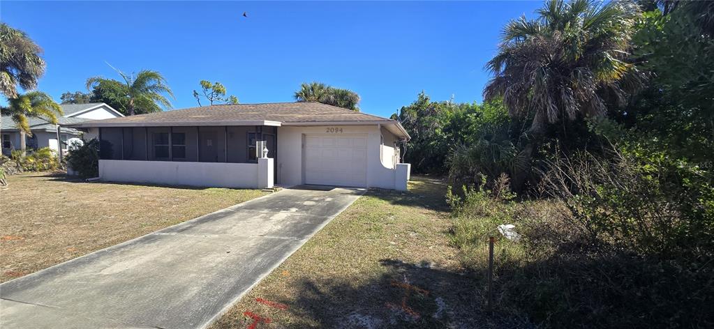 A single-story house with a screened porch, a garage, and a concrete driveway — 2094 CARPETGREEN STREET, PORT CHARLOTTE, FL